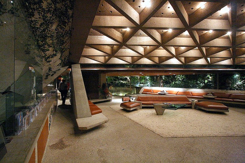 John Lautner: Perhaps the most-seen Lautner house is the Sheats- Goldstein residence. The films “The Big Lebowski”
(1998), “Bandits” (2001), and “Charlie’s Angels: Full Throttle” (2003) are just a few of the many films that have featured the house—also a favorite of photographers. The centerpiece of the design is another concrete roof, which contains three folded, triangular surfaces. Two points touch the ground at different elevations, essentially creating a concrete sail. The interior coffered ceiling rises 18 feet overhead at the tallest point and dives down to almost six feet to allow for shade from the sun. More than 700 small drinking glasses were incorporated into the roof ’s design
to create tiny skylights. (Lautner considered this a way
to recreate the light of a northern Michigan forest.) The natural light also allows the concrete to once again appear weightless—similar to the Garcia residence, but this time trading organic forms for purely geometric ones.
The original clients, Paul and Helen Sheats, sold the house soon after it was completed in 1963. Businessman James Goldstein purchased it in 1972 and worked closely with Lautner on a series of projects to bring the design to perfection. Lautner was free to incorporate new technologies into the ongoing renovations, including concrete-and-steel furniture and a transparent sink that looks like a waterfall when in use and gives the user an uninterrupted view of the landscape.