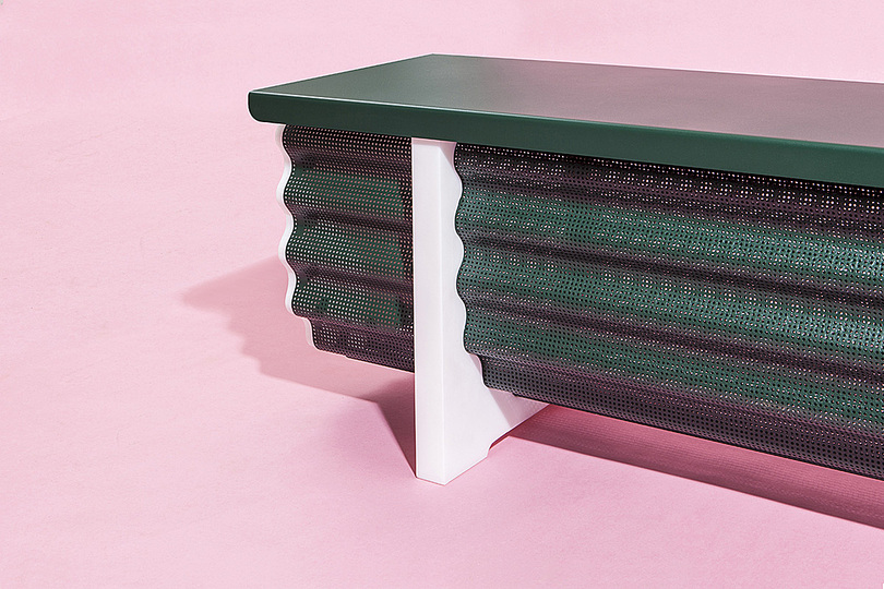 Michael Schoner: 
Crest & Trough is a crossover of different archetypes: a bench, a chest – and in terms of appearance – a trough.

Its storage unit is made from perforated corrugated steel that is resting in a pair of U-shaped legs. As a result those legs as well as the end caps have to follow the bend sinus wave of the container. A lid from folded steel serves as a seat. The furniture is a split up in extrusion elements and those perpendicular to them divides the volume into graphic surfaces.