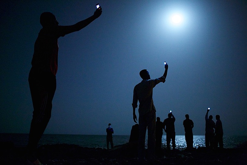 World Press Photo 2014: © John Stanmeyer, USA, VII for National Geographic. African immigrants on the coast of Djibouti are holding up their mobiles to receive telephone signals from nearby Somalia. Djibouti is one of the most frequently used port of Spain by refugees fleeing from Somalia, Eritrea and Ethiopia seeking a better life in Europe and the Middle East.